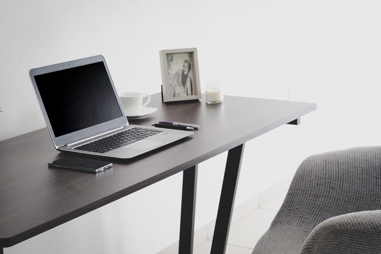 Home-Office-Arbeitsplatz mit Laptop und Notizbuch für digitale Immobilienverwaltung aus der Ferne